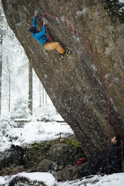 Outdoor winter sport. Rock climber ascending a challenging cliff. Extreme sport climbing.