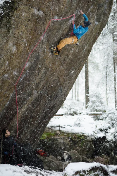 Montañista ascendiendo una roca en el bosque nevado de invierno. Deportes extremos. Naturaleza careliana . — Foto de Stock
