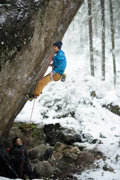 Deportes de invierno al aire libre. Escalador escalando un acantilado desafiante. Escalada deportiva extrema . — Foto de Stock