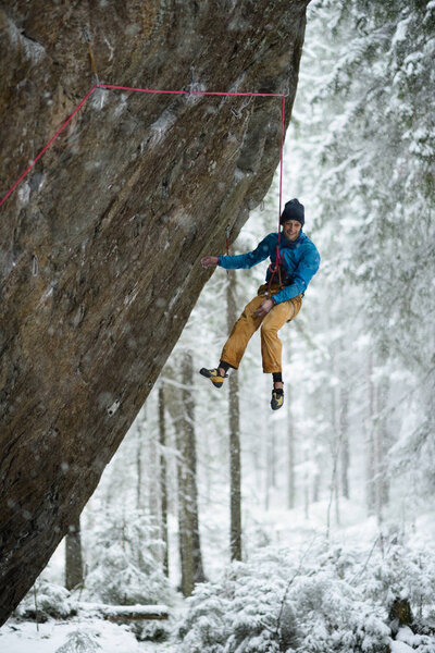 Outdoor winter sport. Rock climber ascending a challenging cliff. Extreme sport climbing. 