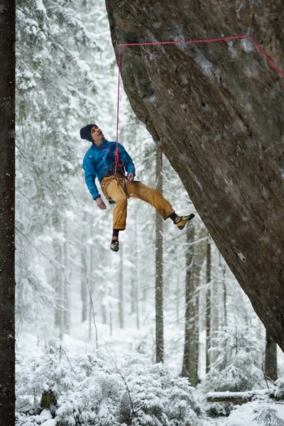Un deporte invernal extremo. Un joven trepando una roca con una barra. Escalada de cuerdas . — Foto de Stock