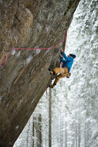 Rock climber on a challenging ascent. Extreme winter climbing.