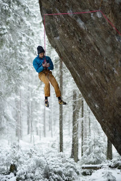 Outdoor winter sport. Rock climber ascending a challenging cliff. Extreme sport climbing.