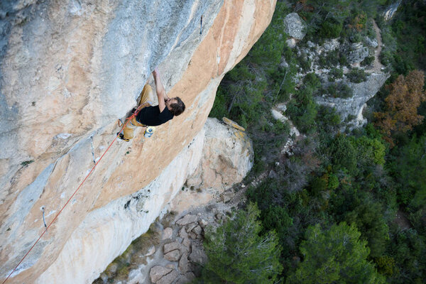 Rock climber ascending a challenging cliff. Extreme sport climbing. Freedom, risk, challenge, success. Siurana, Spain.