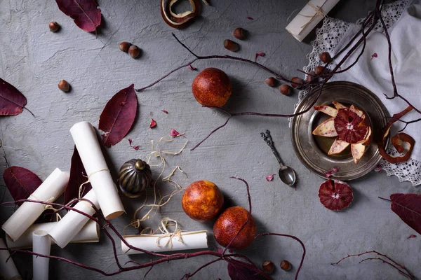 Overhead-Ansicht von roten Orangen auf einem Tisch mit Blättern und Papierrollen. romantische Liebesbriefe oder Hochzeitseinladungen. Ansicht von oben. — Stockfoto