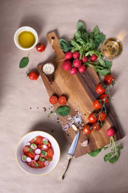 Sağlıklı salata taze olgun yaz sebze malzemeler, domates, turp, baharatlar ve zeytinyağı bir ahşap tahta üzerinde. Üstten Görünüm. 