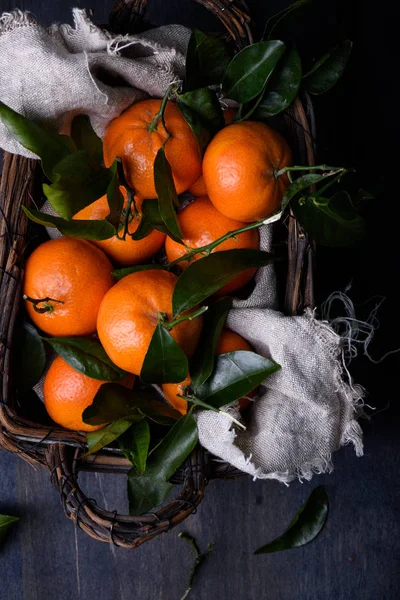 Taze turuncu meyveler, koyu mavi zemin üzerine bir sepet içinde toplandı. Yakın çekim. 