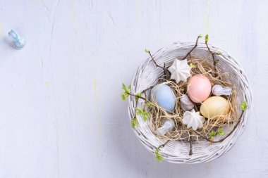 Beyaz arka plan üzerinde renkli yumurtalı Paskalya yuvası. Pastel dekorasyon bahar tatil için. Görünüm alanı Kopyala.