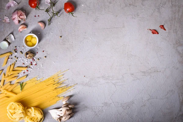 Pasta con ingredientes de cocina en la encimera gris. Receta italiana. Vista desde arriba, copiar espacio . — Foto de Stock
