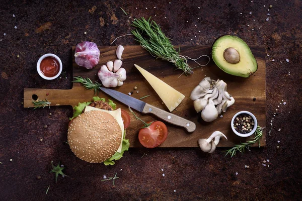 Hamburguesa fresca y sabrosa e ingredientes en tablero de madera. Marco de menú del restaurante, maqueta. Vista superior, espacio de copia . — Foto de Stock