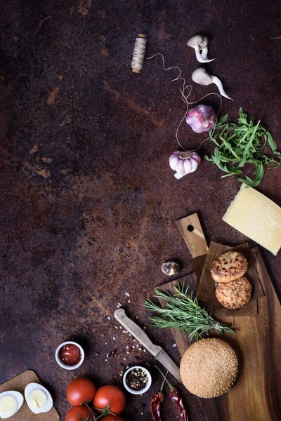 Hamburger fresco fatto in casa su scura tavola da portata con manzo, pomodori, formaggio e uova su sfondo scuro. Vista dall'alto, copia spazio . — Foto Stock
