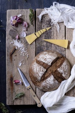 Fırın ürün. Somun ile peynir ve otlar rustik ahşap arka plan üzerinde koyu çavdar ekmeği. Üstten Görünüm.