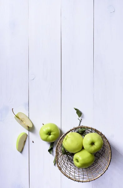 Maçãs verdes maduras e fatia de maçã em uma mesa branca, fru sazonal — Fotografia de Stock
