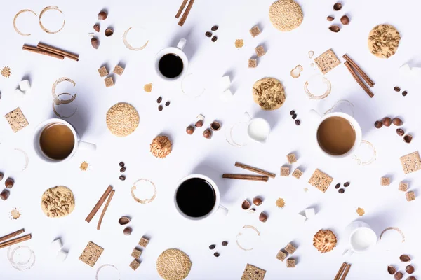 Ассортимент чашек кофе с ингредиентами и печеньем, вид сверху — стоковое фото
