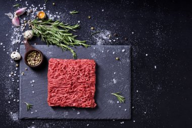 Ham taze mermer kıyma et ve baharat koyu arka plan üzerinde. 
