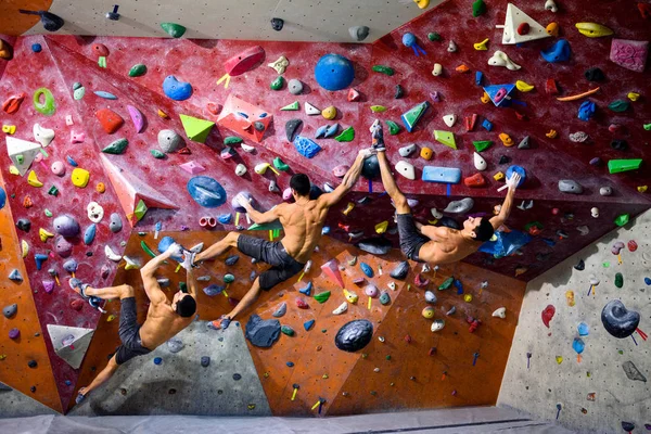 Atletik erkek tırmanma bir spor salonunda eğitim bouldering. Kapalı çalışma — Stok fotoğraf