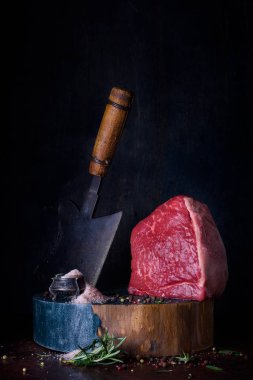 Ham sığır eti biftek, otlar, tahta masada yemek yemek.