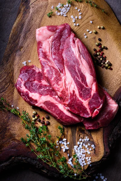 Carne crudă, friptură de vită pe tăietor de lemn, condimente, vedere de sus — Fotografie, imagine de stoc
