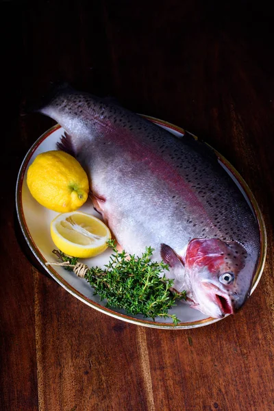 Bir tabak ham alabalık, limon ve otlar. Balık malzemeler çanağı.