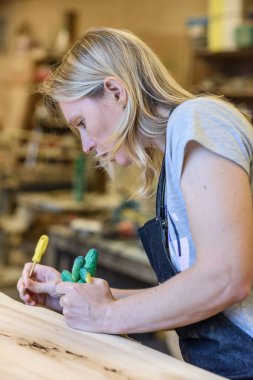 Wood Endüstrisi veya Kereste Endüstrisi 'nin içinde özel sektör, orman ürünleri üretimi. Kadın marangoz mobilya ürünleri yapıyor, atölyesinde maske ve eldiven takıyor.. 