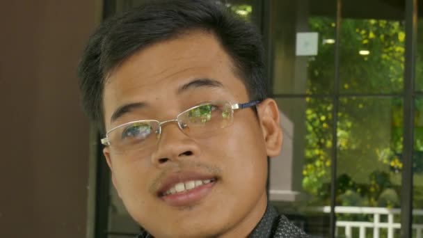 CU молодого азиатского мужчины-специалиста, смотрящего вверх от телефонного звонка — стоковое видео