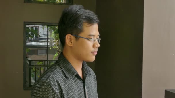 Média close up de jovem asiático profissional do sexo masculino no perfil como ele contempla seu negócio — Vídeo de Stock