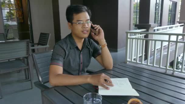 Средний взгляд на молодого азиатского профессионала, делающего телефонный звонок коллеге — стоковое видео
