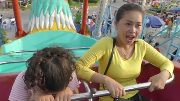 PHNOM PENH, CAMBODIA: 17 de mayo de 2017 - Vista media de la madre y la hija de una familia multicultural en el columpio del parque de atracciones — Vídeo de stock