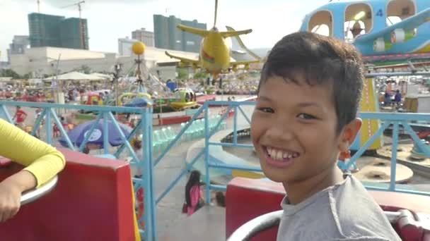Азіатський хлопчик їде зі своєю сім'єю на парк атракціонів гойдалки їздити в Азії (повільний рух) — стокове відео