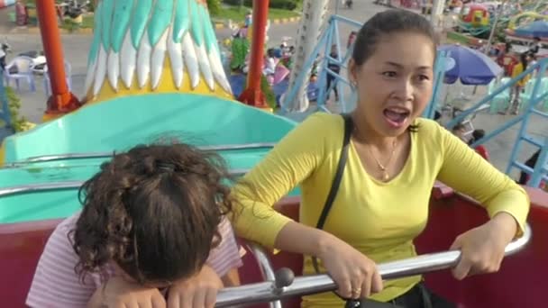 Phnom Penh, Kamboçya - 17 Mayıs 2017: Orta görünümünü anne ve çok kültürlü bir ailenin kızı Asya (yavaş hareket eğlence parkı salıncak binen) — Stok video
