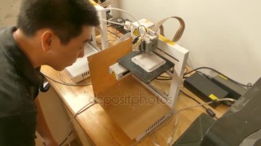Yüksek açı görünümü teknisyen monitörler 3d printerlere harcama maddeler bir maker's atölyesinde