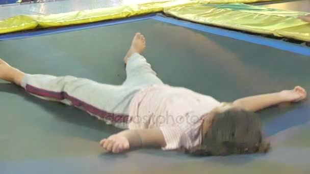 Una muchacha asiática multicultural rebota sobre su espalda en un trampolín en un parque de atracciones en el sudeste asiático — Vídeos de Stock