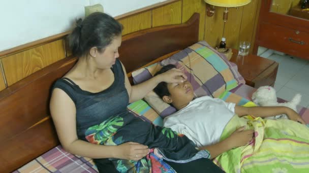 Wielokulturowym matka opiekuje się jej syn chory, ktory lezy w łóżku kaszel — Wideo stockowe