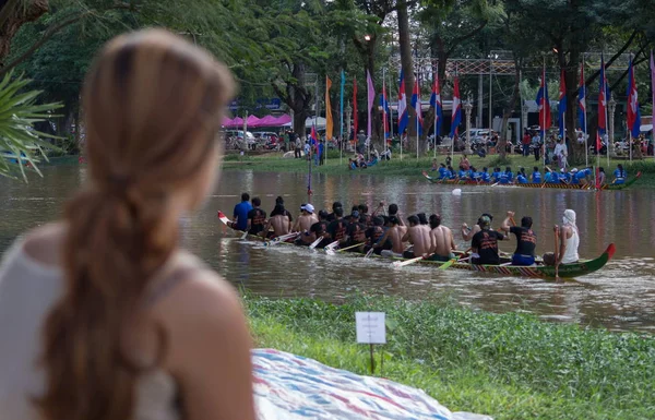 SIEM REAP, CAMBODIA - NOVEMBRO 2016: Vista da espectadora ocidental assistindo a uma corrida de barco tradicional cambojana Imagem De Stock