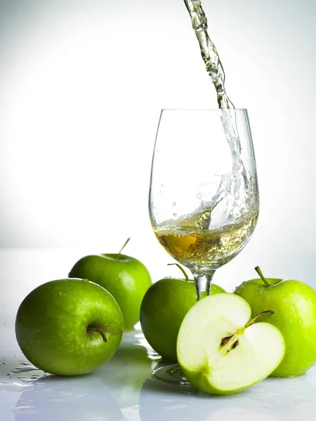 Pouring apple juice in glass and apples