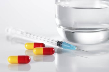 Beyaz arka planda şırınga ve haplar