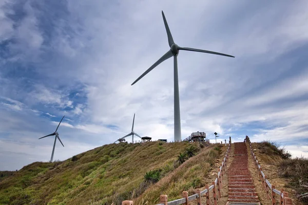 low angle view of big windmills near stairs on blue sky background