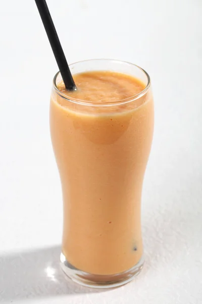 Closeup of glass with papaya milk tea and drinking straw