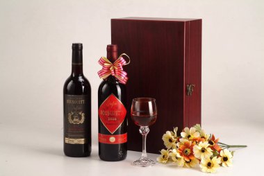 İki şişe kırmızı şarap giftbox, cam ve beyaz arka plan üzerinde çiçekler