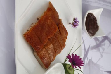 Çiçekli beyaz tabakta kavrulmuş domuz closeup