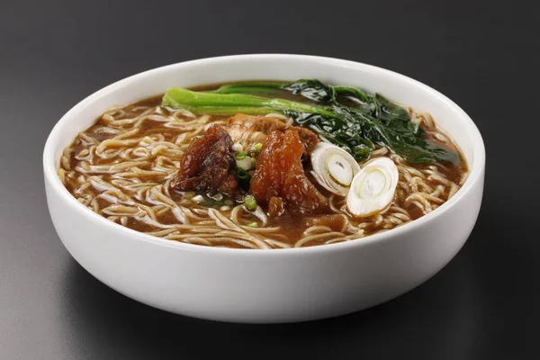 Closeup of bowl with beef noodle soup on table