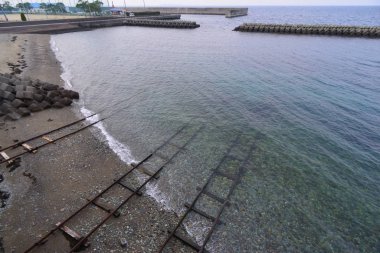 Deniz kıyısında, suda kumların üzerinde merdivenler var.