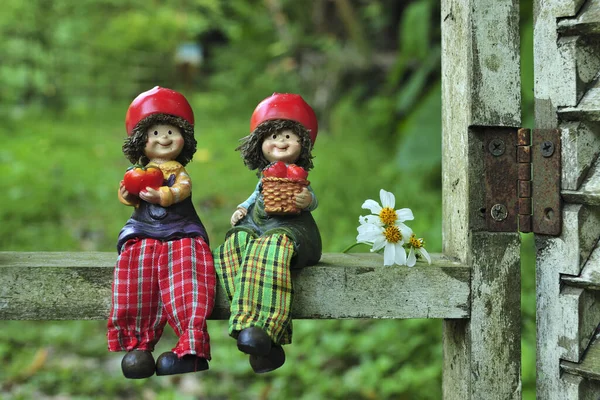 Duas bonecas sentadas no trilho de madeira — Fotografia de Stock