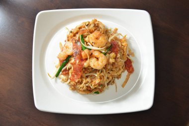 Dikdörtgen beyaz tabakta servis edilen deniz ürünleri eriştesi.