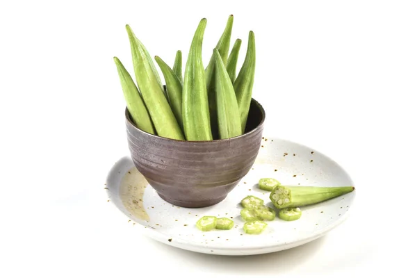 Okra y okra en rodajas en el plato en el fondo blanco — Foto de Stock