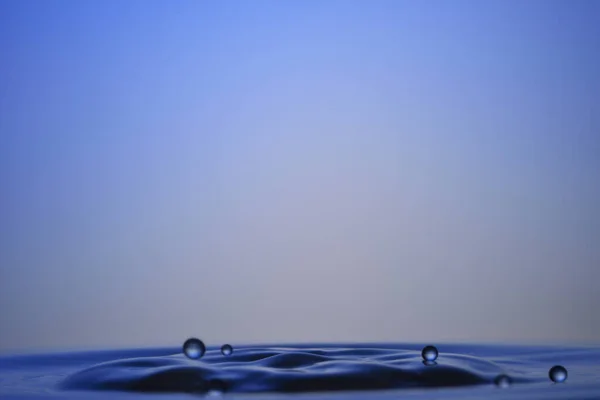 High-speed photography falling water drops into water — Stock Photo, Image