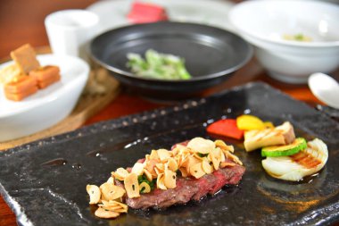 Siyah tabakta dilimlenmiş et ve sebze.