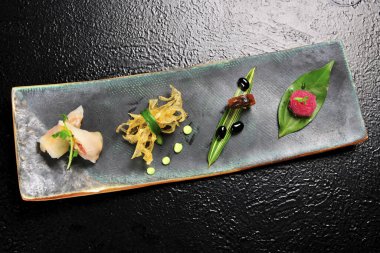 Siyah masadaki tabakta çeşitli yemekler var.