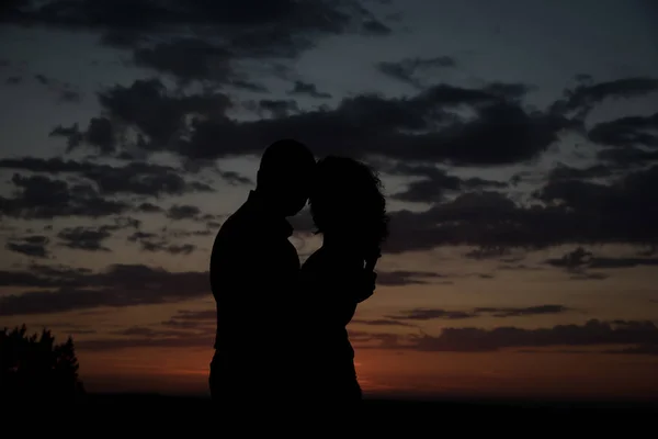 Silhouettes of lovers boys and girls against the evening sky and — Stock Photo, Image