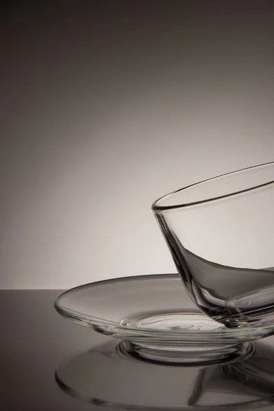 Glas leerer Becher mit Tee und Untertasse auf schwarz-weißem Hintergrund — Stockfoto